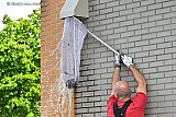 18-05-2022 Breda - Terwijl zijn collegas op het dak van de supermarkt de waterafvoer doorspuiten met een brandslang vangt een brandweerman beneden met een net eendjes die in de waterafvoer vielen op bij de dakoverstort.
 - Fotokrant