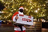 22-12-2020 Breda - De Kerstman met mondkapje op bij de kerstboom op de Grote Markt in Breda. De kerstman sjouwt een van z'n kerstpakketten die opgeslagen lagen op de Noord Pool mee naar de woning van een medewerker van OnLogic die hij er in de avond mee gaat verrassen. - Fotokrant