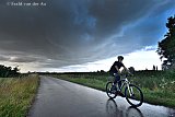 21-07-2025 Breda - Noodweer nadert de stad. Een overvallen wielrenner rijd snel de polder uit ivm het naderende onweer.   - Fotokrant