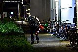 20-08-2021 Breda - Met verkeerskkegels in zijn hand zoekt een agent voor een appartenmentencomplex naar kogelhulzen. - Fotokrant